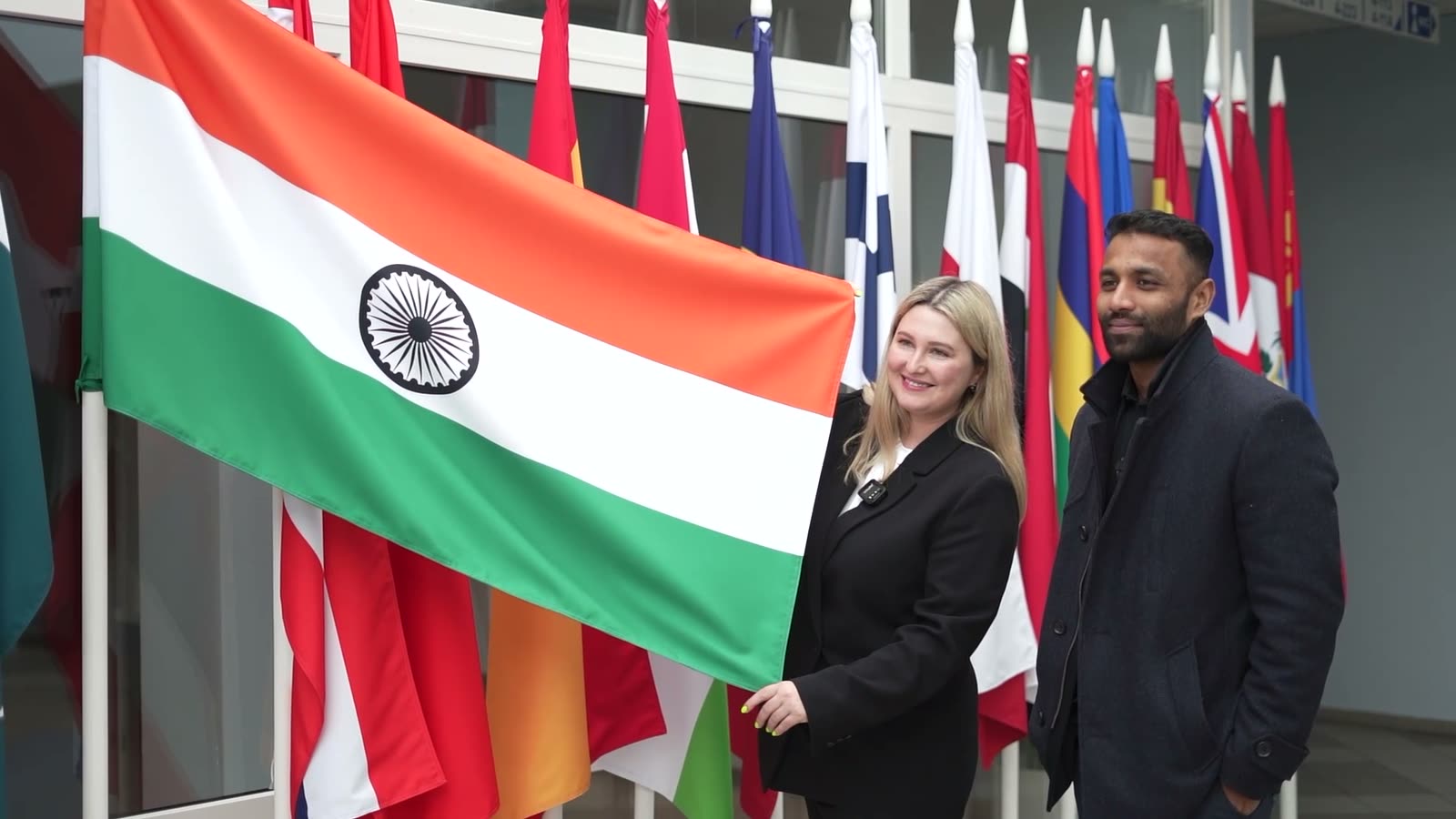A TSI representative and our colleague beside the Indian flag, in front of a row of national flags at TSI