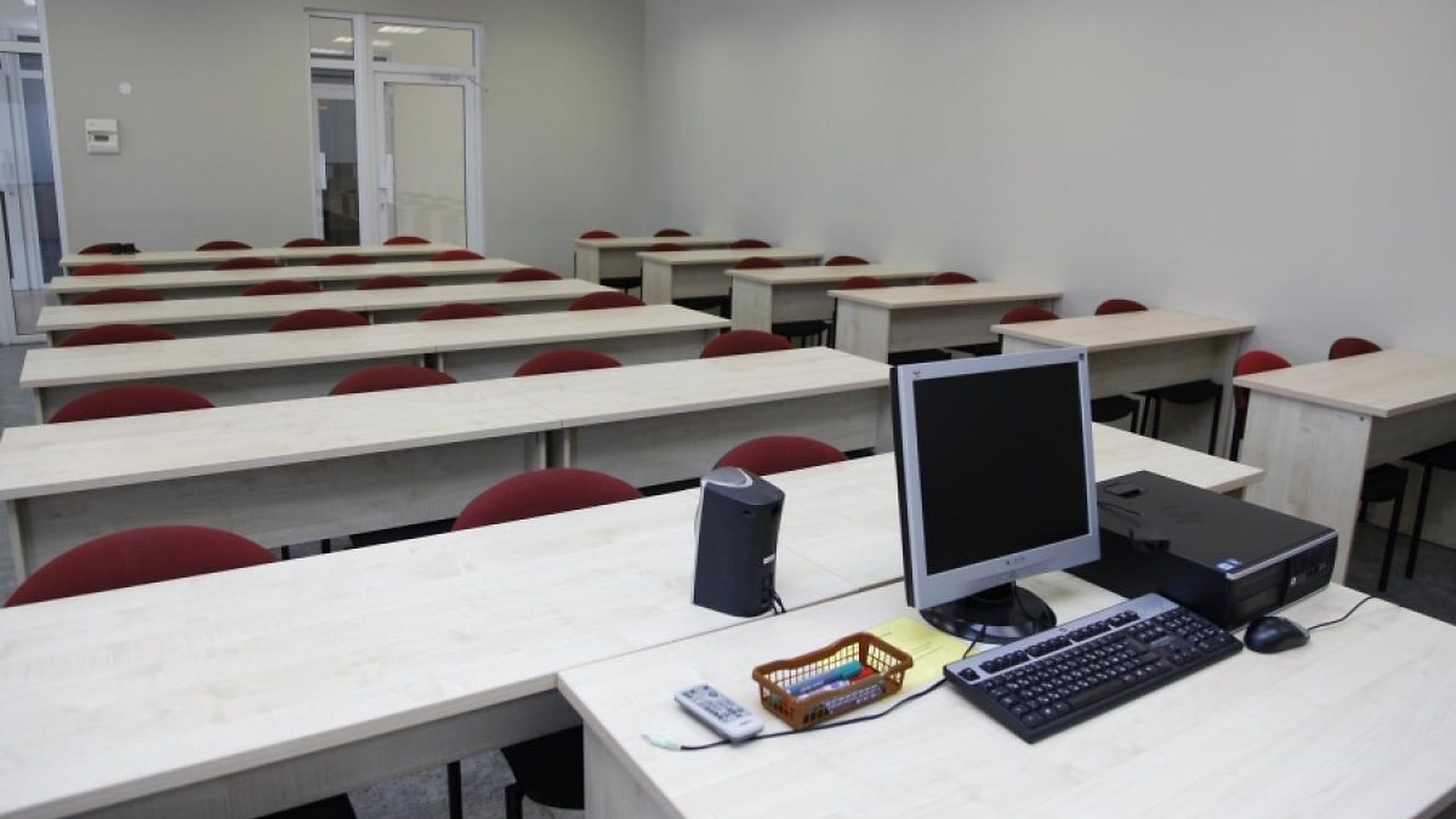 A classroom at Turība: rows of desks with red chairs and a computer at the front