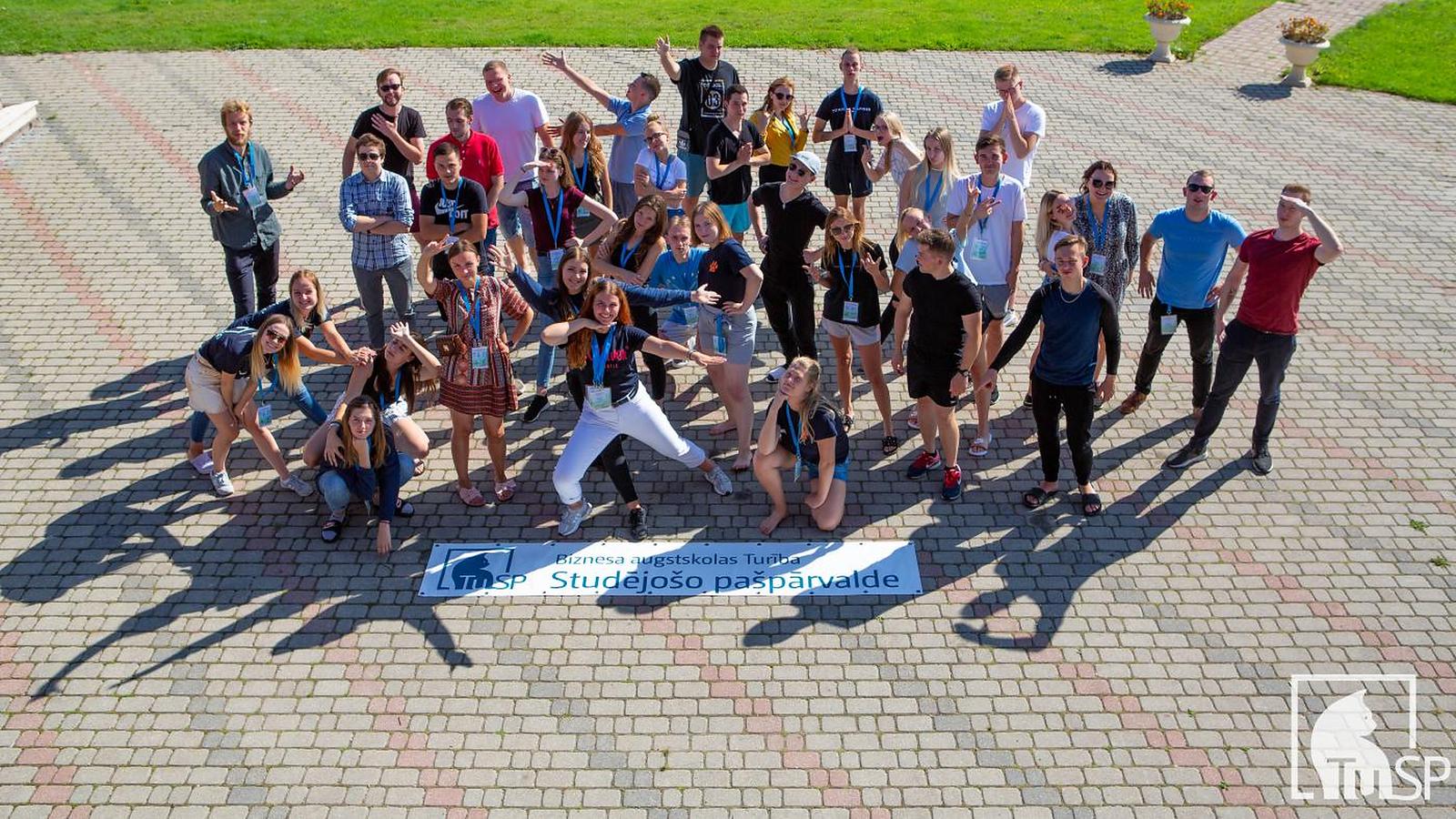 Turība's student council posing together outdoors around their banner, “Biznesa augstskolas Turība Studējošo pašpārvalde”